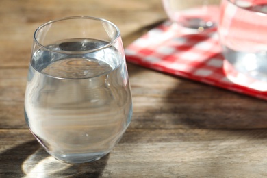 Glass of water on wooden table, closeup with space for text. Refreshing drink