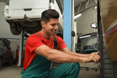 Photo of Professional mechanic changing wheel at automobile repair shop