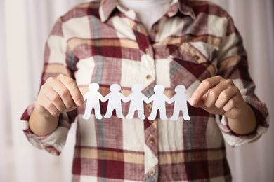 Woman holding paper people chain indoors, closeup. Unity concept