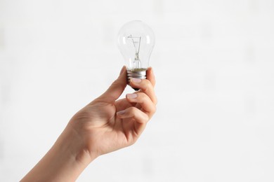 Photo of Woman holding light bulb on white background, closeup. Space for text