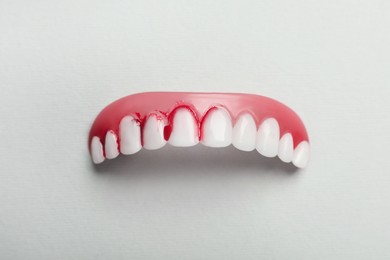 Gum model with blood on teeth against white background, top view