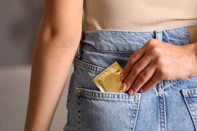 Photo of Mother putting condom into daughter's jeans pocket at home, closeup. Sex education concept