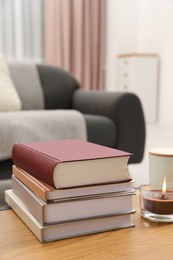 Photo of Books and burning candle on wooden table indoors, space for text