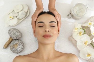 Young woman receiving facial massage in spa salon, top view