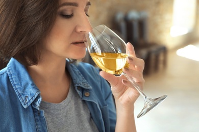 Woman with glass of white wine indoors, closeup