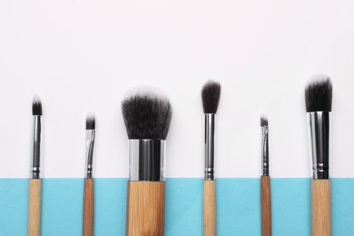 Different makeup brushes on color background, flat lay
