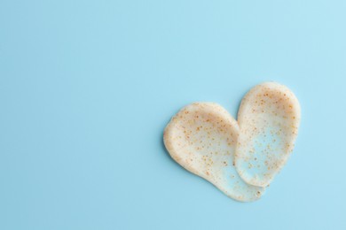 Samples of face scrub in shape of heart on light blue background, top view. Space for text