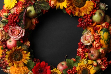 Beautiful autumnal wreath with flowers, berries and fruits on black background, closeup. Space for text