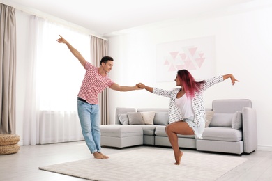 Beautiful happy couple dancing in living room at home