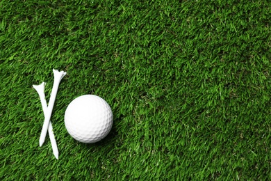 Golf ball and tees on artificial grass, top view with space for text