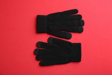 Pair of stylish woolen gloves on red background, flat lay