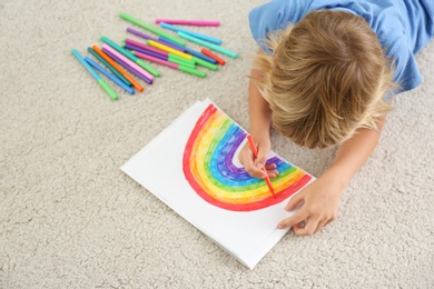 Little boy drawing rainbow on floor indoors, above view. Stay at home concept