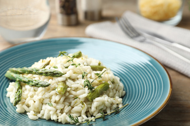 Delicious risotto with asparagus served on wooden table, closeup
