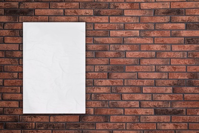 Blank creased poster on brick wall. Mockup for design 