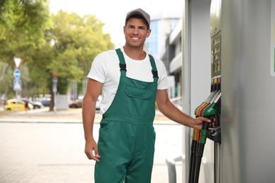 Worker taking fuel pump nozzle at modern gas station