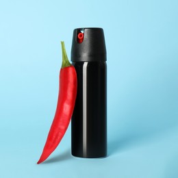 Image of Bottle of pepper spray and red hot chilli on turquoise background