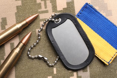 Photo of Military ID tag, bullets and patch on pixel Ukrainian camouflage, flat lay
