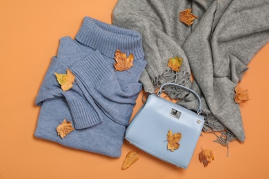 Flat lay composition with sweater and dry leaves on orange background. Autumn season