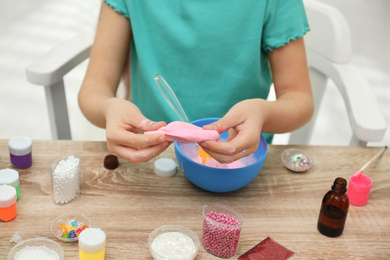 Little girl making DIY slime toy at table indoors, closeup