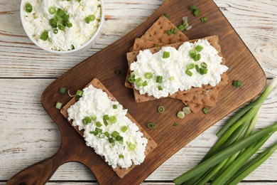 Photo of Crispy crackers with cottage cheese and green onion on white wooden table, flat lay