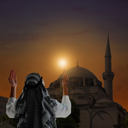 Muslim man praying near mosque at sunset