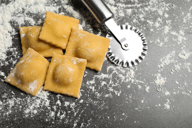 Ravioli and cutter on grey table, above view. Italian pasta