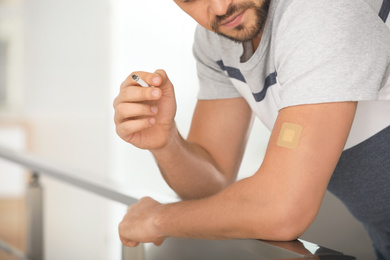 Man with nicotine patch and cigarette indoors, closeup