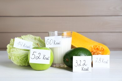 Food products with calorific value tags on white wooden table. Weight loss concept