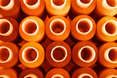 Set of orange sewing threads as background, top view