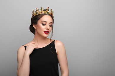 Photo of Beautiful young woman wearing luxurious crown on light grey background, space for text
