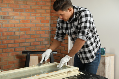 Man repairing old damaged window at table indoors