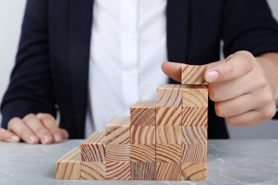 Businesswoman building steps with wooden blocks at table, closeup. Career ladder