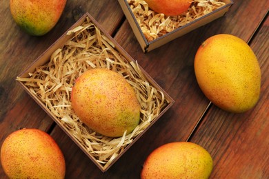 Delicious ripe juicy mangos on wooden table, flat lay