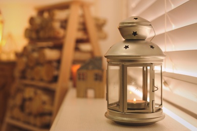 Photo of Decorative Christmas lantern with burning candle near window, space for text