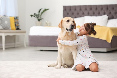 Adorable yellow labrador retriever and little girl at home