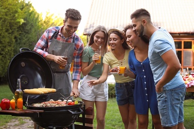 Group of friends with drinks near barbecue grill outdoors
