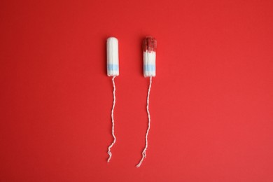 New and used tampons on red background, flat lay
