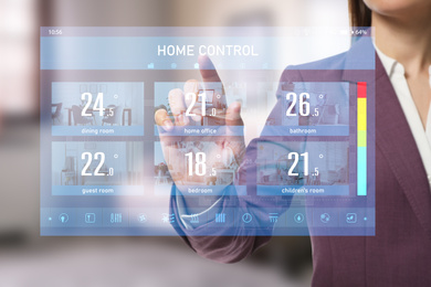 Woman using touchscreen panel to set indoor temperature, closeup. Smart home automation system