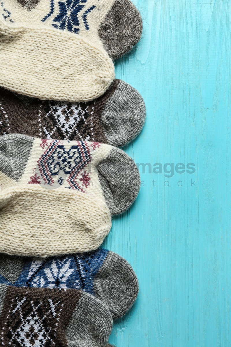 Soft knitted socks on light blue wooden background, flat lay with space for text. Winter clothes