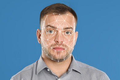 Facial recognition system. Young man with biometric identification scanning grid on light blue background