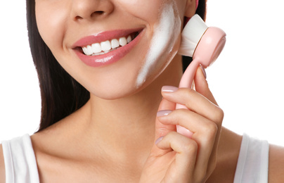 Young woman using facial cleansing brush on white background, closeup. Washing accessory