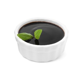 Photo of Balsamic glaze with basil leaves in bowl isolated on white