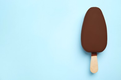 Ice cream glazed in chocolate on light blue background, top view. Space for text