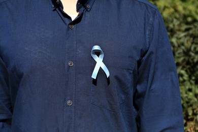 Man with light blue ribbon outdoors, closeup. World Diabetes Day