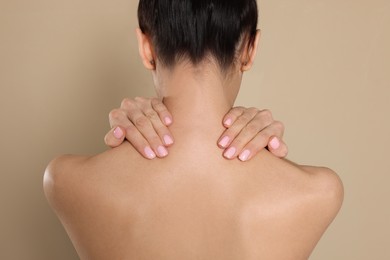 Back view of woman with perfect smooth skin on beige background, closeup