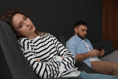 Man preferring smartphone over his girlfriend at home, focus on woman. Relationship problems