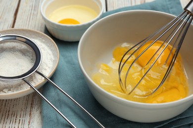 Whisking eggs in bowl on wooden table, closeup