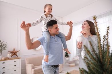 Happy family with cute child decorating Christmas tree at home