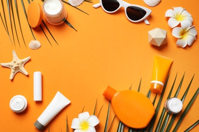 Flat lay composition with sun protection cosmetic products on orange background, space for text