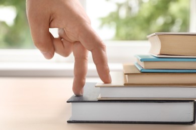 Photo of Woman imitating stepping up on books with her fingers indoors, closeup
